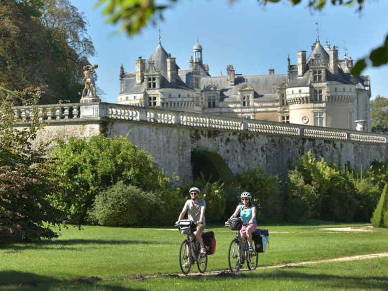 2 voyageurs à vélo passent au pied du Château du Lude sur l'itinéraire de la Vallée de la Loir à Vélo