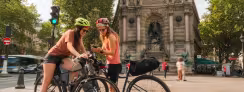 Deux cyclistes consultent leur itinéraire sur smartphone place Saint-Michel à Paris, point de départ de la Véloscénie vers Mont-Saint-Michel.
