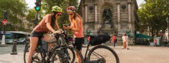 Deux cyclistes consultent leur itinéraire sur smartphone place Saint-Michel à Paris, point de départ de la Véloscénie vers Mont-Saint-Michel.