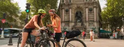 Deux cyclistes consultent leur itinéraire sur smartphone place Saint-Michel à Paris, point de départ de la Véloscénie vers Mont-Saint-Michel.