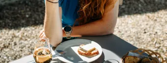 Cycliste attablée en terrasse devant une planche de charcuterie et fromages locaux chez un prestataire Accueil Vélo