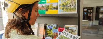 Arrêt à l'office de tourisme pour une cycliste en route sur l'itinéraire Paris Mont-Saint-Michel