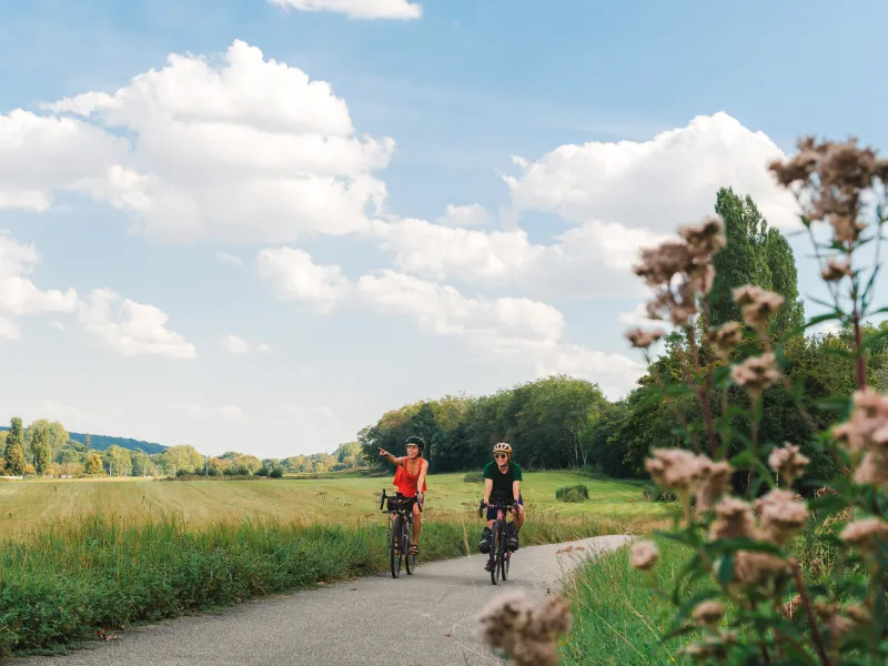 Deux cyclistes sur la piste cyclable de la Véloscénie en Essonne, entre champs et prairies