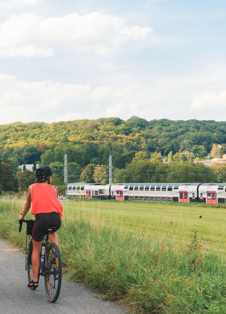 Deux cyclistes le long de la Véloscénie regardent un train passer en vallée de la Bièvre