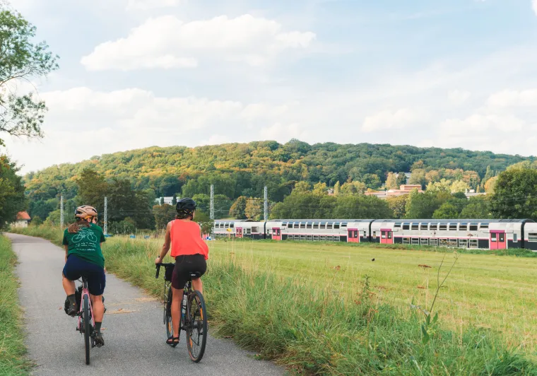 Deux cyclistes le long de la Véloscénie regardent un train passer en vallée de la Bièvre