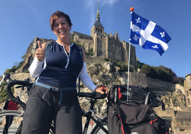 Josiane et son vélo orné d'un drapeau du Québec à son arrivée au Mont Saint-Michel le long de La Véloscénie