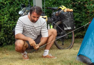 Voyageur à vélo plantant sa tente le long de la Véloscénie