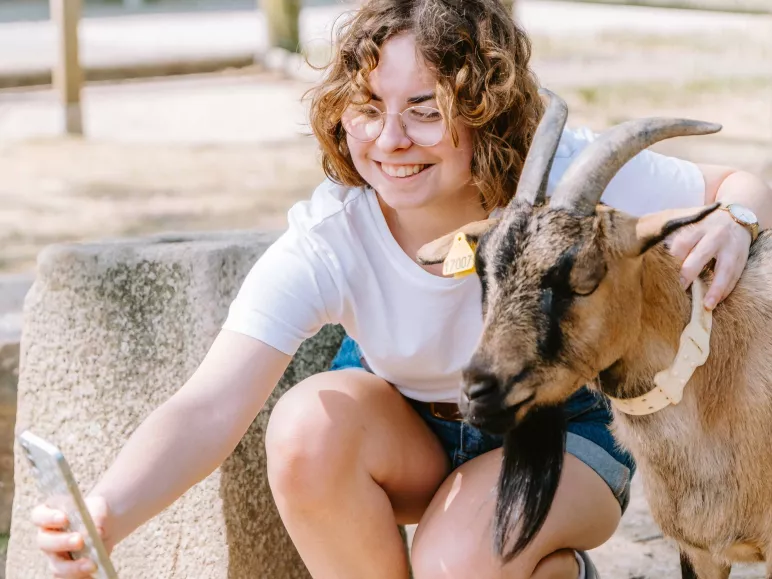 Une jeune femme se prend en photo avec une chèvre dans l'enclos de la Bergerie Nationale de Rambouillet