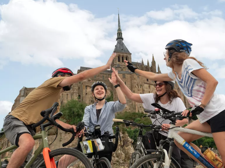 Cyclistes se tapant dans la main au pied du Mont Saint-Michel